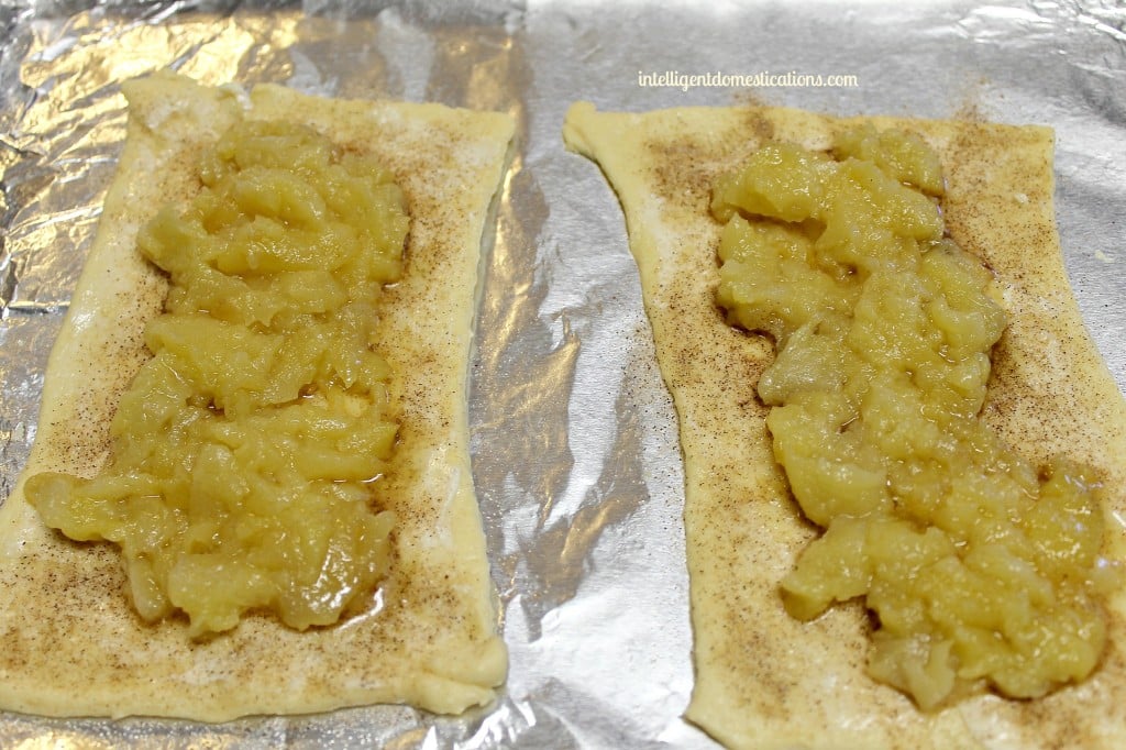 This 4 Ingredient Crescent Apple Turnover recipe will have your house smelling delicious and tickle your taste buds too. It's an easy recipe using Crescent rolls and apples drizzled with homemade icing. #crescentrolls #appledessert #fallfood crescent rolls with cooked apples on top
