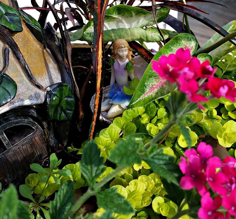 Our Fairy Garden Fairy Princess sitting on a tree stump next to her cottage. My Fairy Garden Tour 2016. Fairy Garden Ideas. Flowers to use in a flower garden. #fairygarden #gnomes #fairygardenideas 