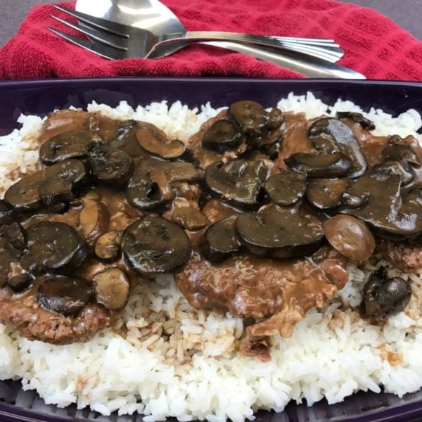Crockpot Cubed Steak and Mushroom Gravy is served on a bed of rice for an easy weeknight meal