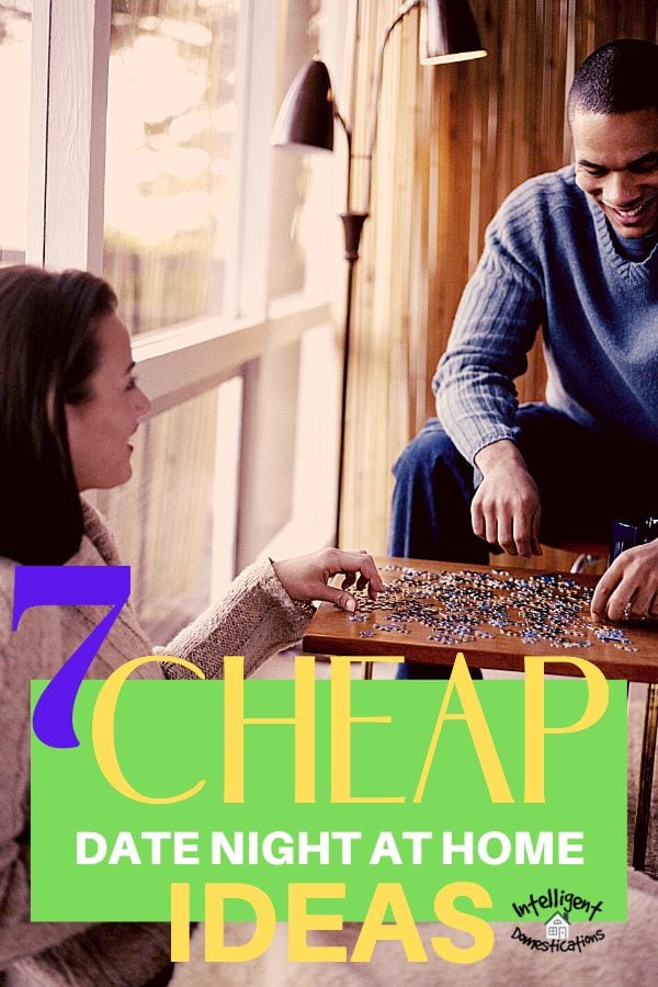 A young couple putting a puzzle together on a small table next to a window