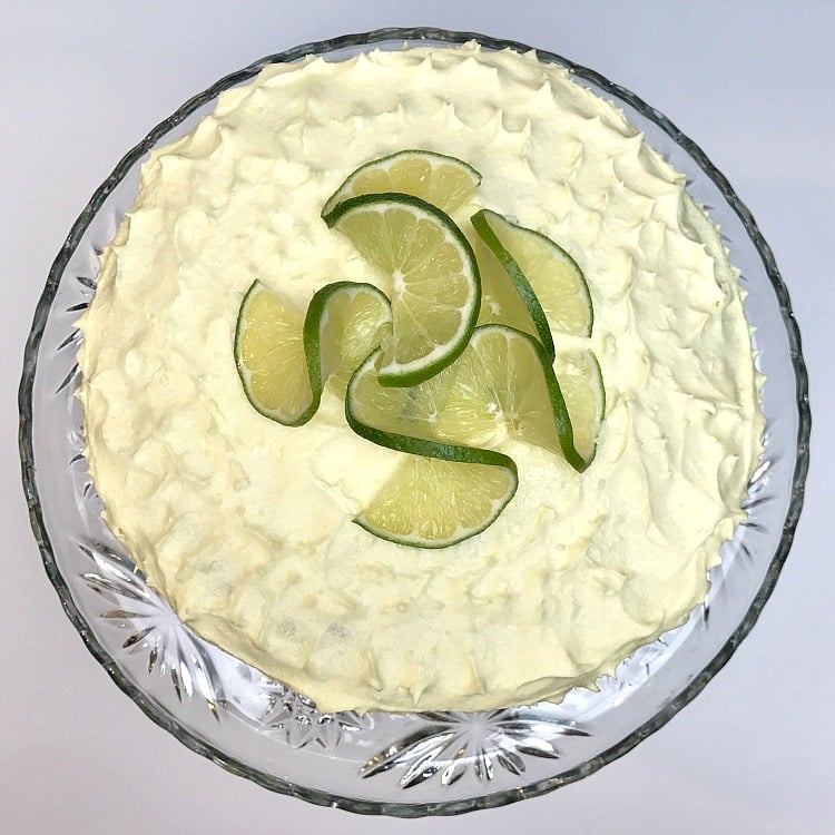 a round cake with lime slices swirled on top sitting on a cake plate