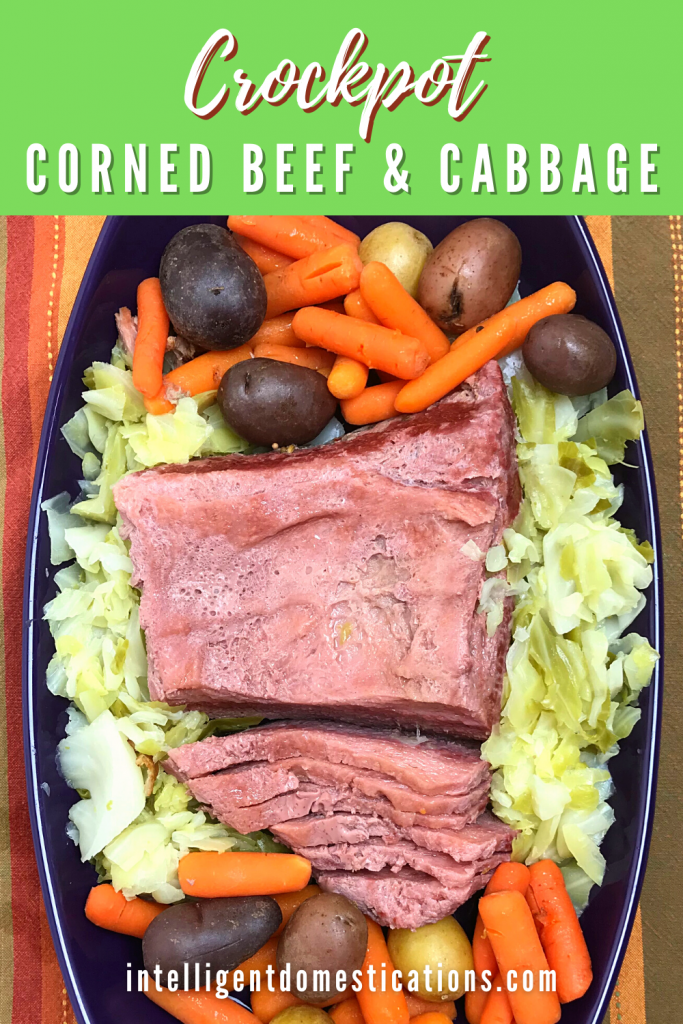 Cooked Corned beef brisket, cabbage, carrots and potatoes in a purple serving dish on a table