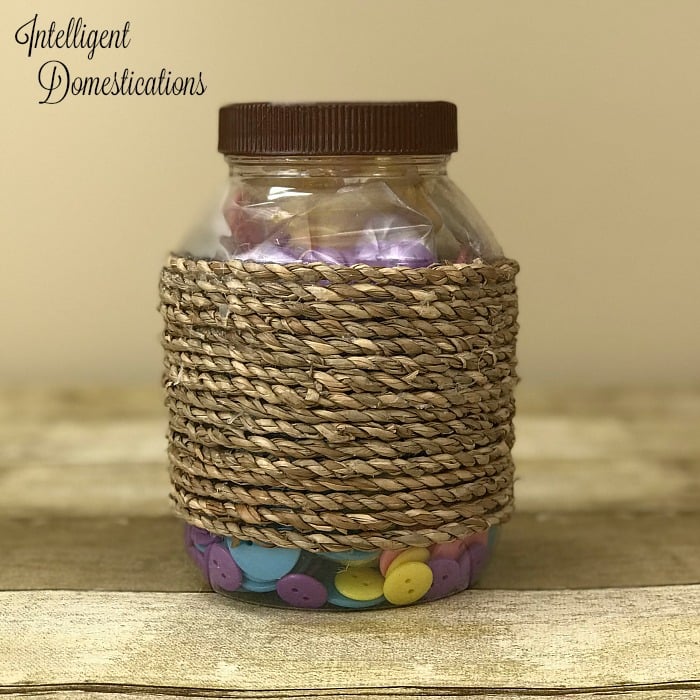 Hot glue rope onto the side of a repurposed mayonnaise jar to create a pretty storage container. Repurpose mayonnaise jars into pretty craft room supply storage containers. Craft room organization. Repurpose mayonnaise jars. Use pretty craft paper to decorate lids of upcycle mayonnaise jars #craftroomorganization