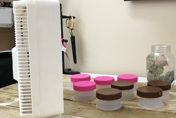 Use a fan to speed the drying process of painted mayonnaise jar lids. Repurpose mayonnaise jars into pretty craft room supply storage containers. Craft room organization. Repurpose mayonnaise jars. #craftroomorganization