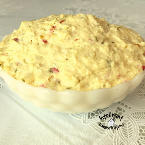 Potato Salad in a white bowl on a table with a white tablecloth
