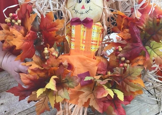 How To Make A Scarecrow Wreath using Dollar store supplies. Fall Wreath tutorial using faux fall leaves and a Scarecrow for the center. #fallwreath #diyfallwreath #scarecrowwreath #diydecor #craft #fallcraft #fall