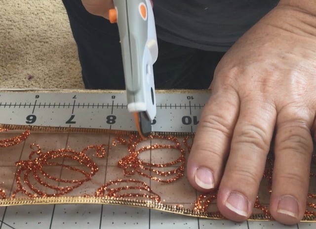 someone cutting orange ribbon using a rotary cutter