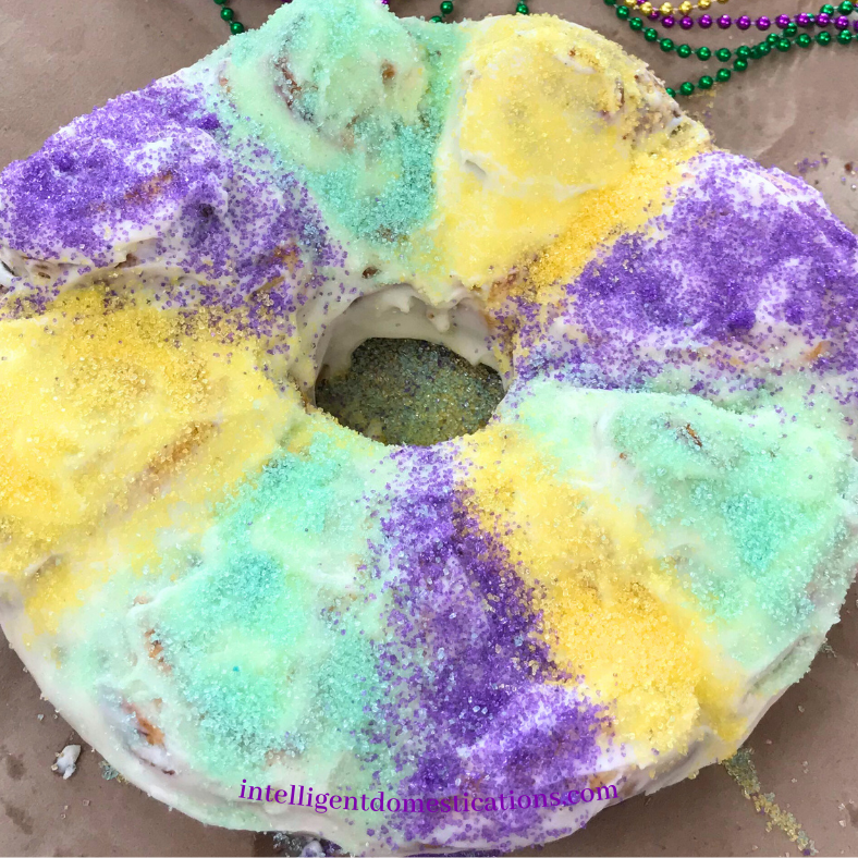 Mardi Gras King Cake made with cinnamon rolls and decorated in Mardi Gras colors with candy sprinkles