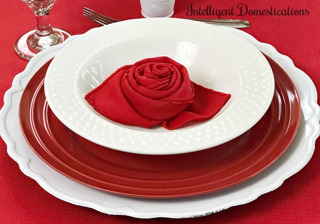 Simple Valentine's Table Decor Ideas using what we have. Rose folded napkins along with a layered red and white table setting create this pretty Valentines Tablescape. #Valentinestabledecor #valentines