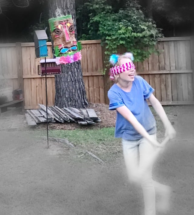 A girl wearing a blindfold swatting at a Pinata