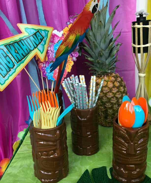 Luau party table with decorations including pineapples and Tiki torches