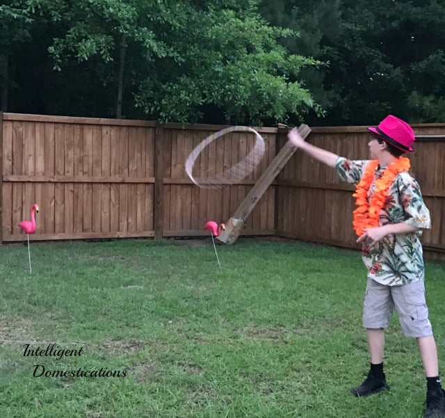 A boy playing a Pink Flamingo Ring Toss game outside