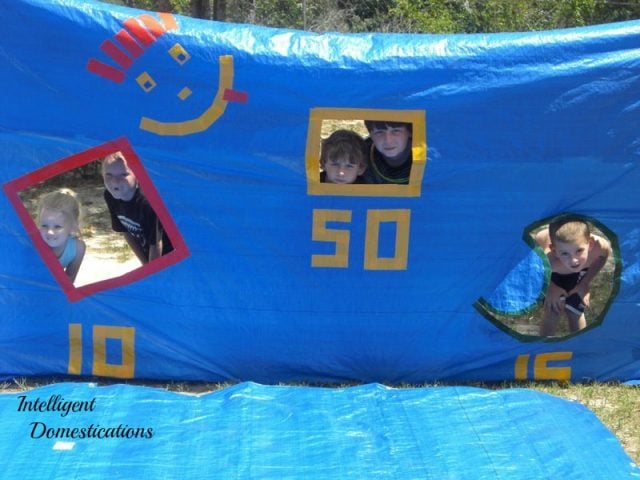 This one DIY Water Tarp Game will keep the kids busy with backyard summer water activities for hours! It's versatile for playing in the water. Play Water Balloon games, Water Bomb Target competitions. Pool Noodle Sword Fighting and a Slip and Slide surface and even use the Target Backdrop as a Photo spot! #watergames #summergames #outdoorplay This one DIY Water Tarp Game will keep the kids busy with backyard summer water activities for hours! It's versatile for playing in the water. Play Water Balloon games, Water Bomb Target competitions. Pool Noodle Sword Fighting and a Slip and Slide surface and even use the Target Backdrop as a Photo spot! #watergames #summergames #outdoorplay