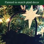 Wood silhouette nativity ornament painted black with a silver star hanging on a Christmas tree