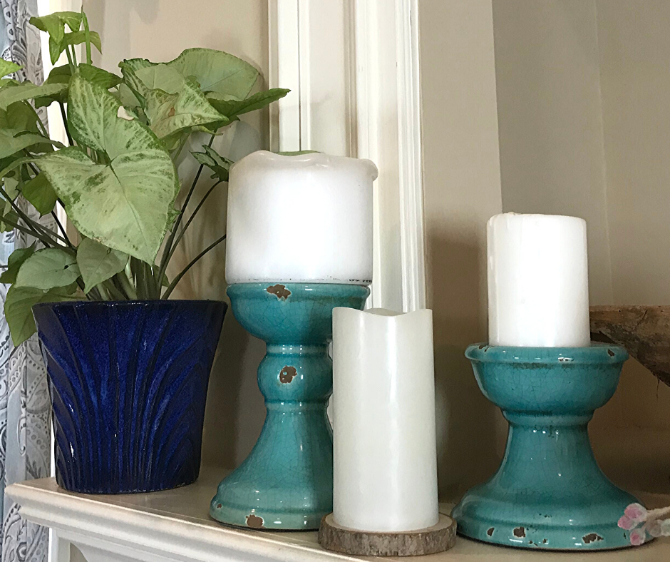 Tips for Decorating a Spring Mantle with plants, candles and greenery. I used what I had on hand including old candle holders which can double as cake plate stands. A live houseplant anchors this little mantle vignette.