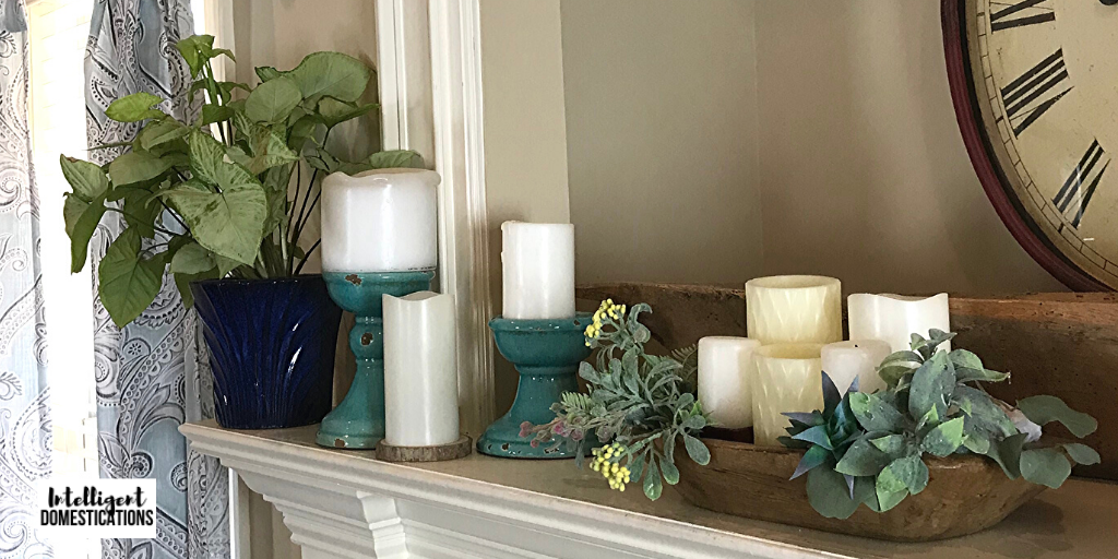 Decorating a large mantle for Spring using mini vignettes. Candles, faux greenery and a live plant decorate this mantle for Spring on a budget. 