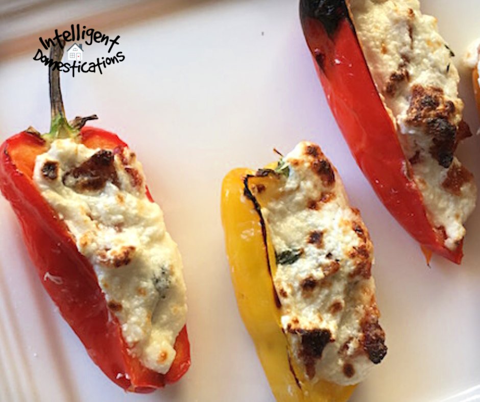 Orange and yellow cheese stuffed sweet peppers displayed on a white dish