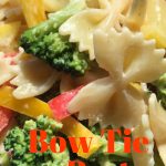Close up image of Bow Tie Pasta salad with red and yellow sliced bell peppers and broccoli florets drizzled in dressing