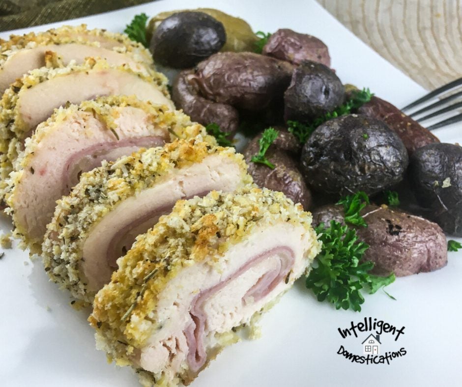 Stuffed rolled chicken breast pictured next to boiled potatoes with the skin on. Chicken Cordon Bleu