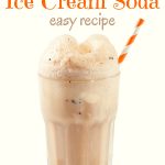 A tall glass filled with Chocolate Ice Cream Soda with an orange and white straw on a white background