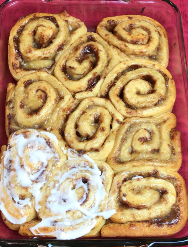 Cinnamon rolls being iced after baking