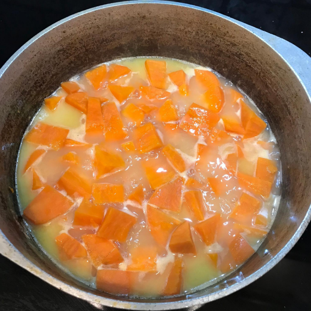 Chopped yams boiling on the stove in an iron pot