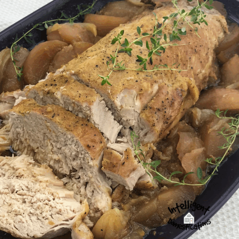Baked Pork Tenderloin surrounded with baked apples and covered with Thyme in a casserole dish