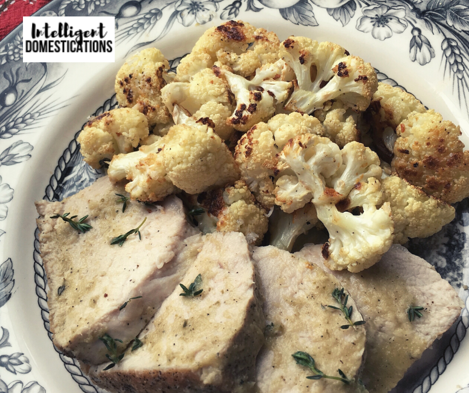 Roasted cauliflower served with sliced pork loin on a dinner plate