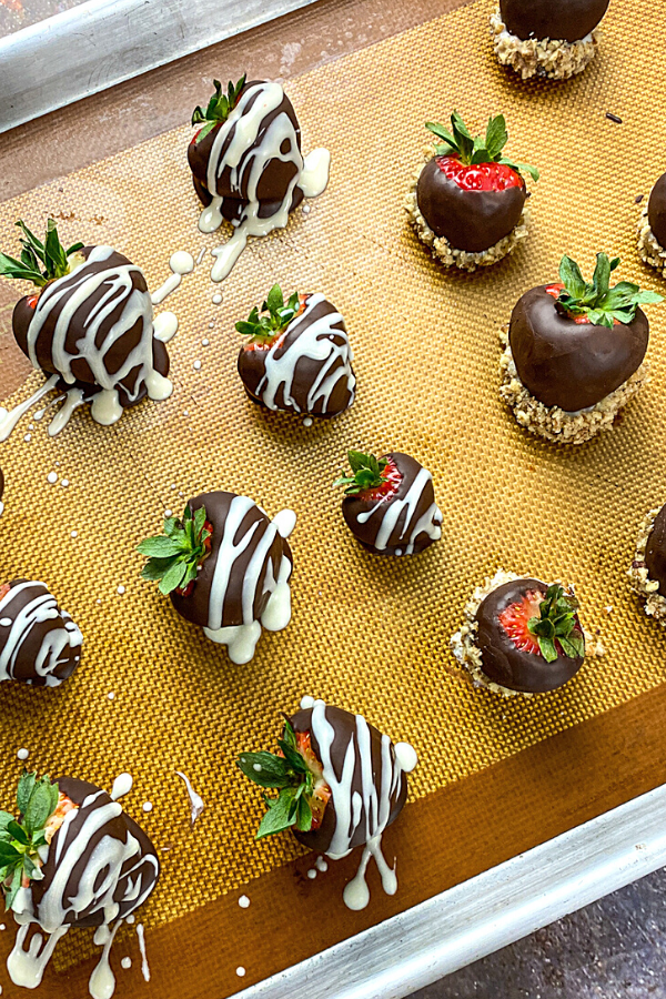 Strawberries dipped in chocolate and pecans on a baking sheet