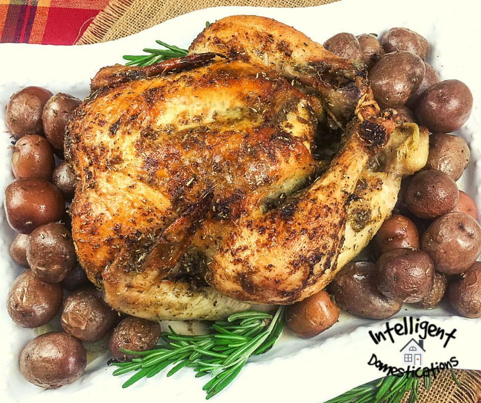 oven roasted chicken and red potatoes on a white platter with sprigs of thyme