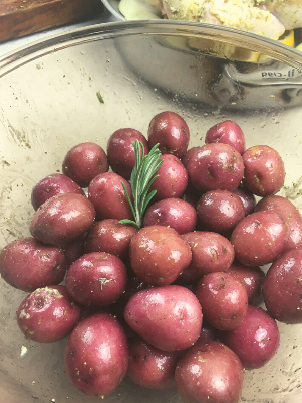 baby red potatoes in a bowl with oil and rosemary sprigs