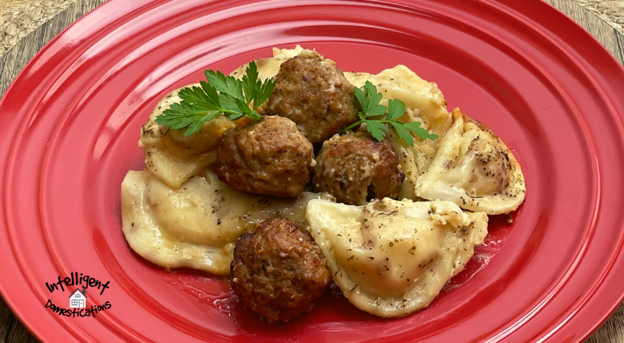 Pierogi's and meatballs on a red dish with alfredo sauce