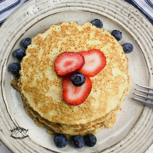 a stack of pancakes with blueberries and strawberries on top