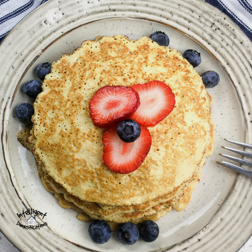 a stack of pancakes with blueberries and strawberries on top