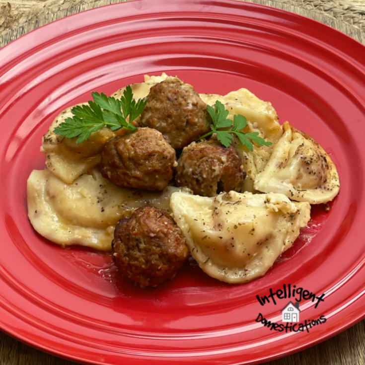 Pierogi and Meatballs Alfredo served on a red dish