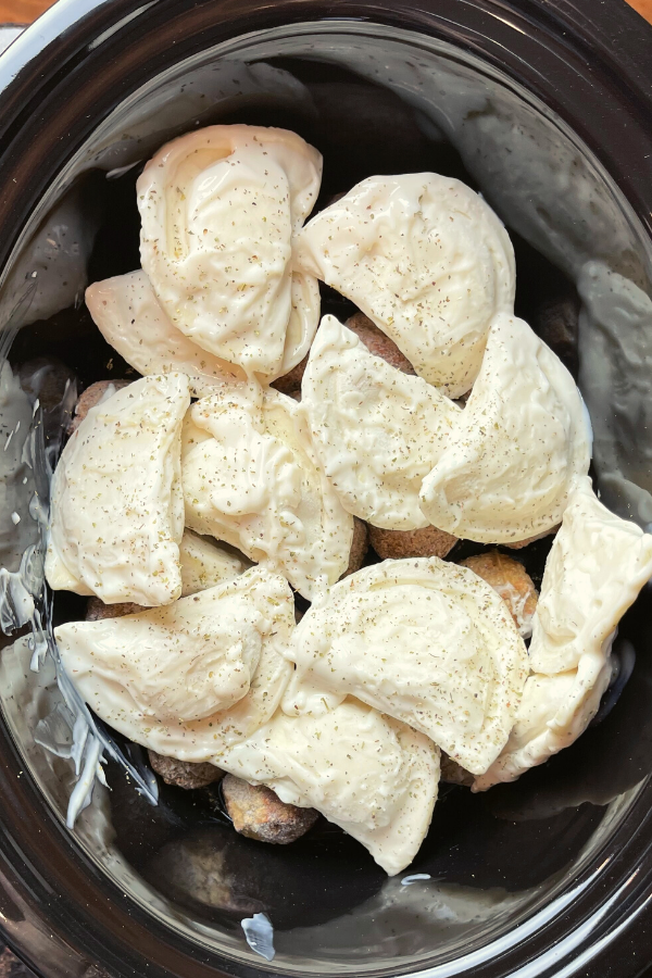 frozen pierogies on top of meatballs in a Crockpot