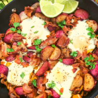 an iron skillet filled with eggs, radishes, peppers and bacon