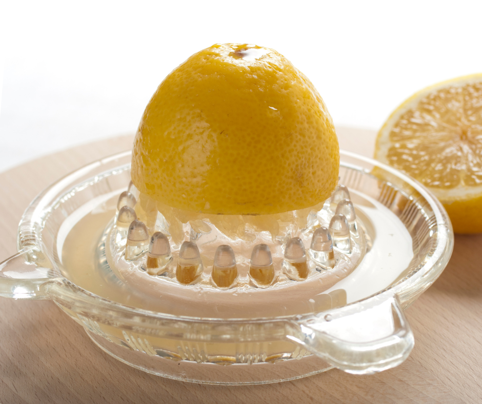juicing a lemon in a glass juicer