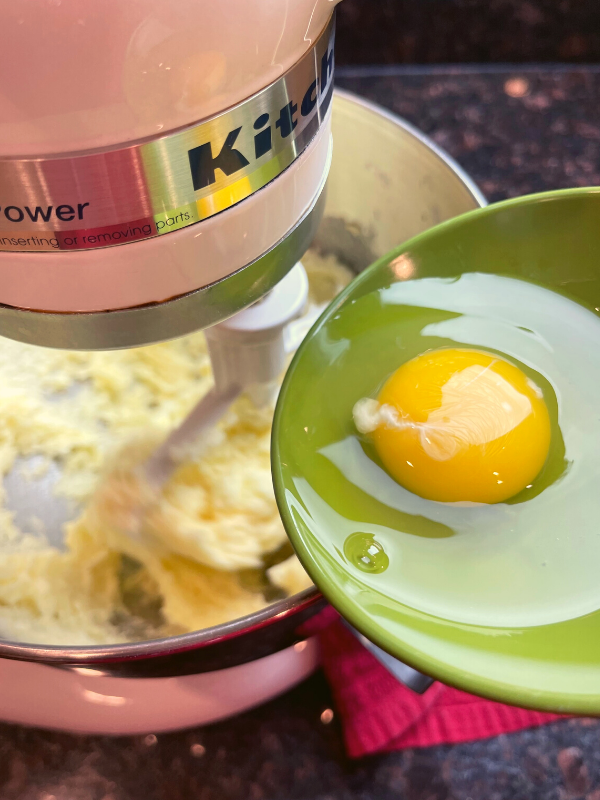 adding an egg to cake batter while mixing