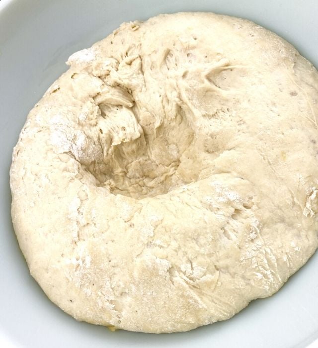 Pretzel dough in a glass bowl punched down after rising. Now ready to be used