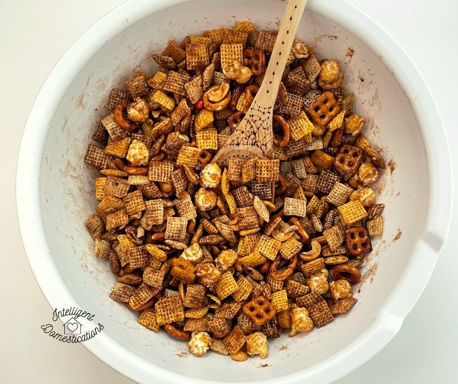Pumpkin spice Chex mix being blended with seasoning in white bowl