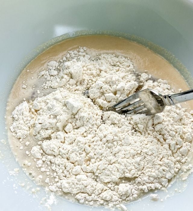 mixing the flour into the wet ingredients to make homemade soft pretzels