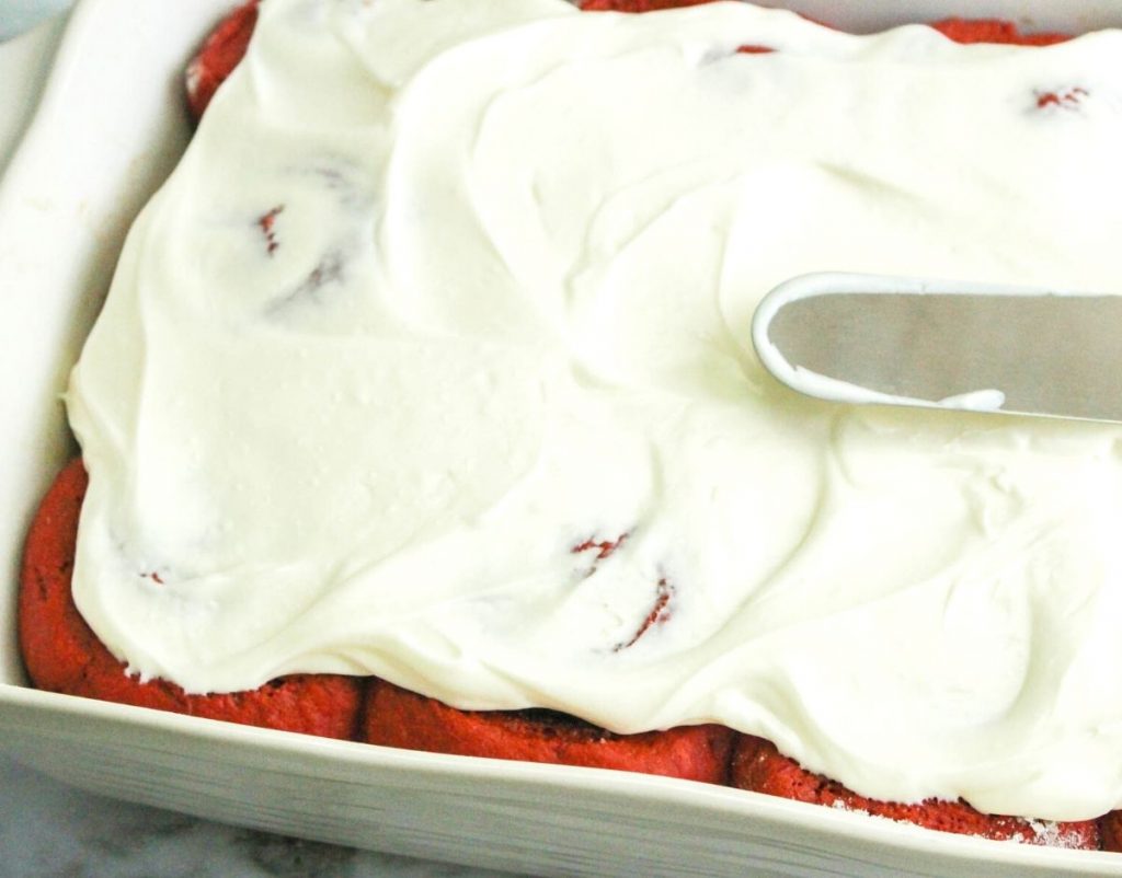 Icing the cinnamon rolls in the pan