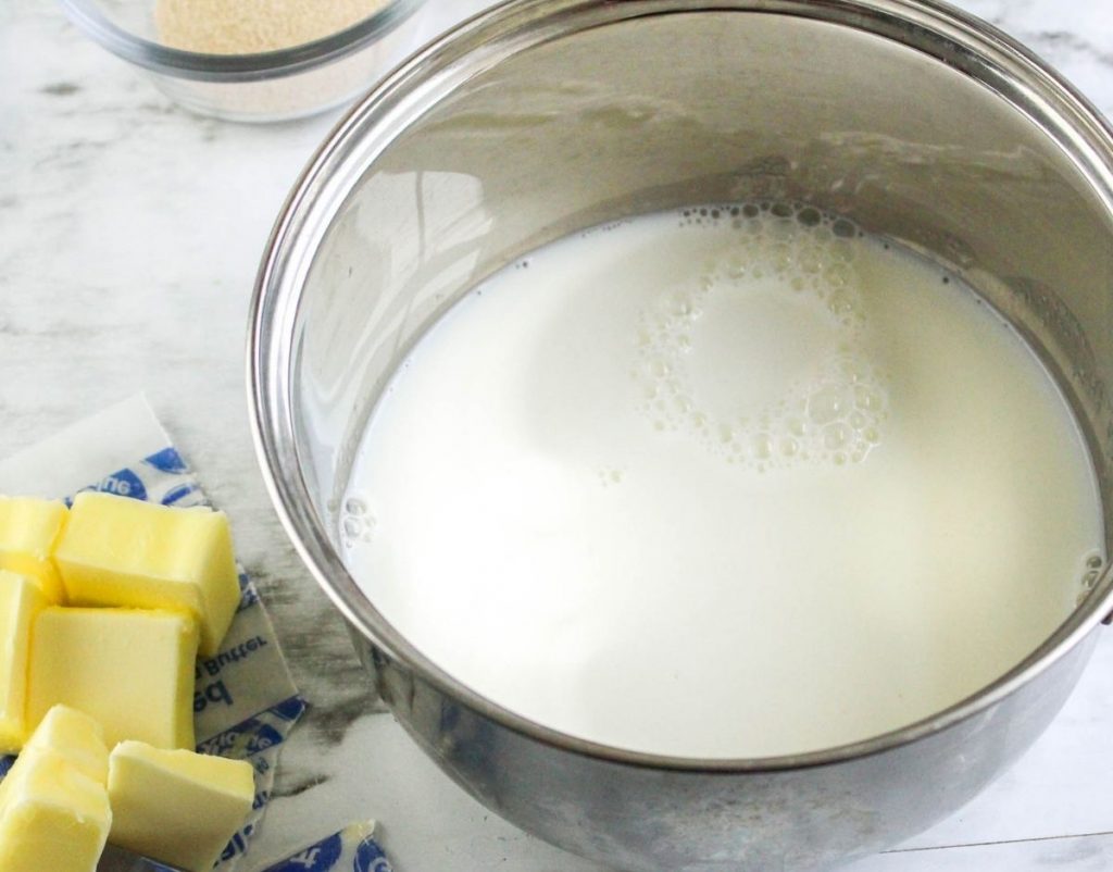 Milk in saucepan with cut up butter next to it