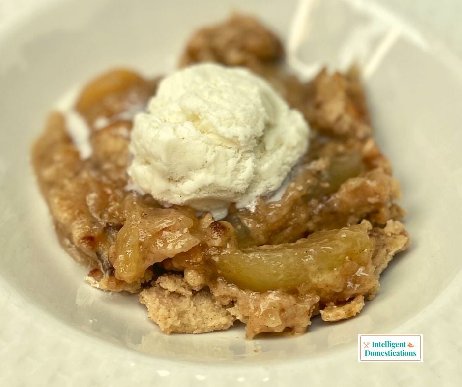 Apple Dump Cake in a bowl with vanilla ice cream on top