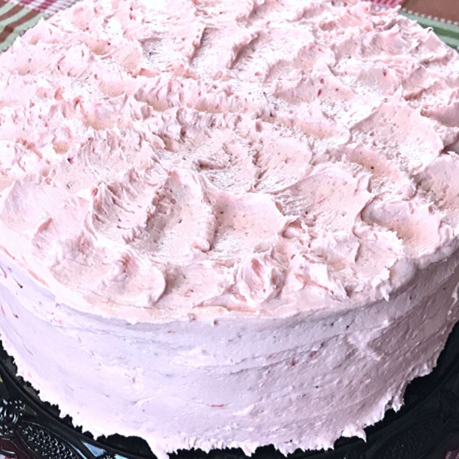 A strawberry cake with strawberry buttercream frosting swirled on top