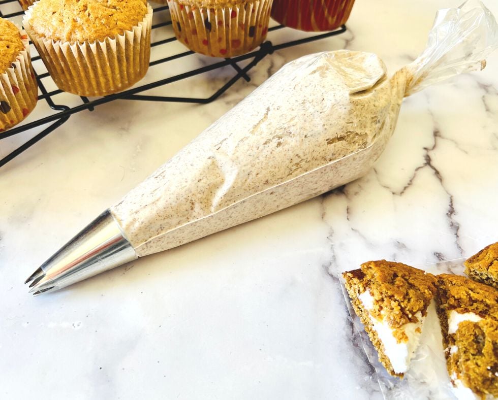 frosting in a piping bag next to cupcakes