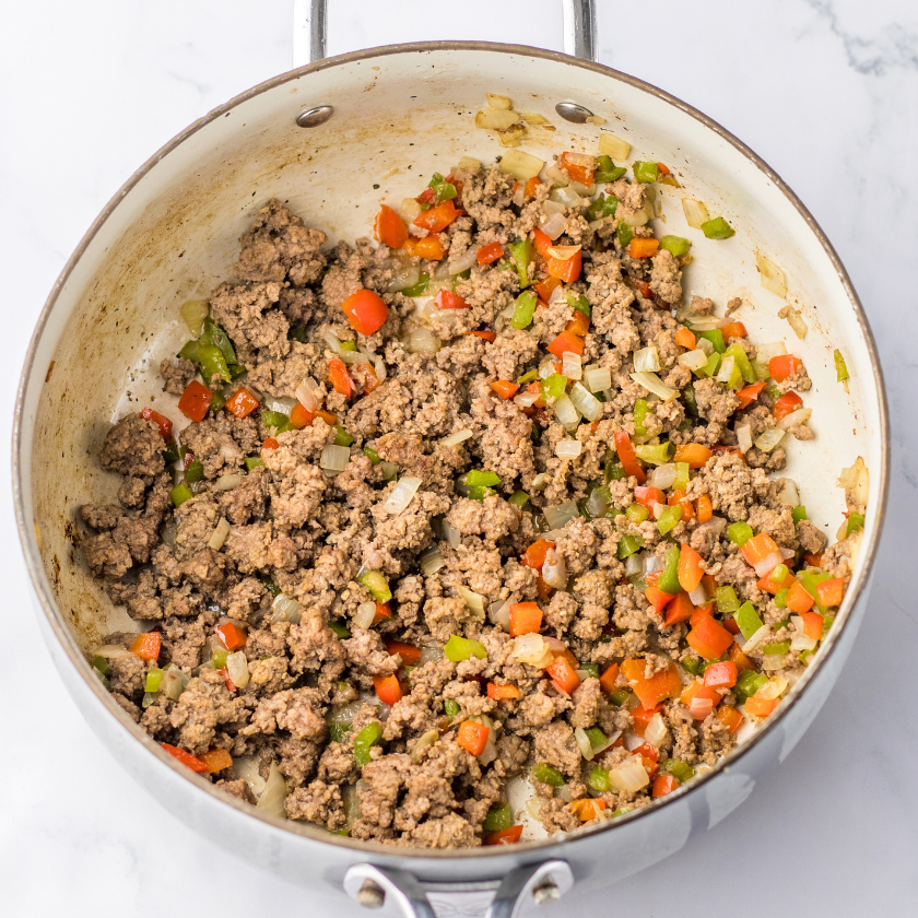 ground beef with onions and bell peppers browned in a skillet