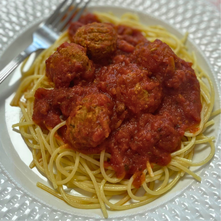 a plate of spaghetti and meatballs covered in sauce