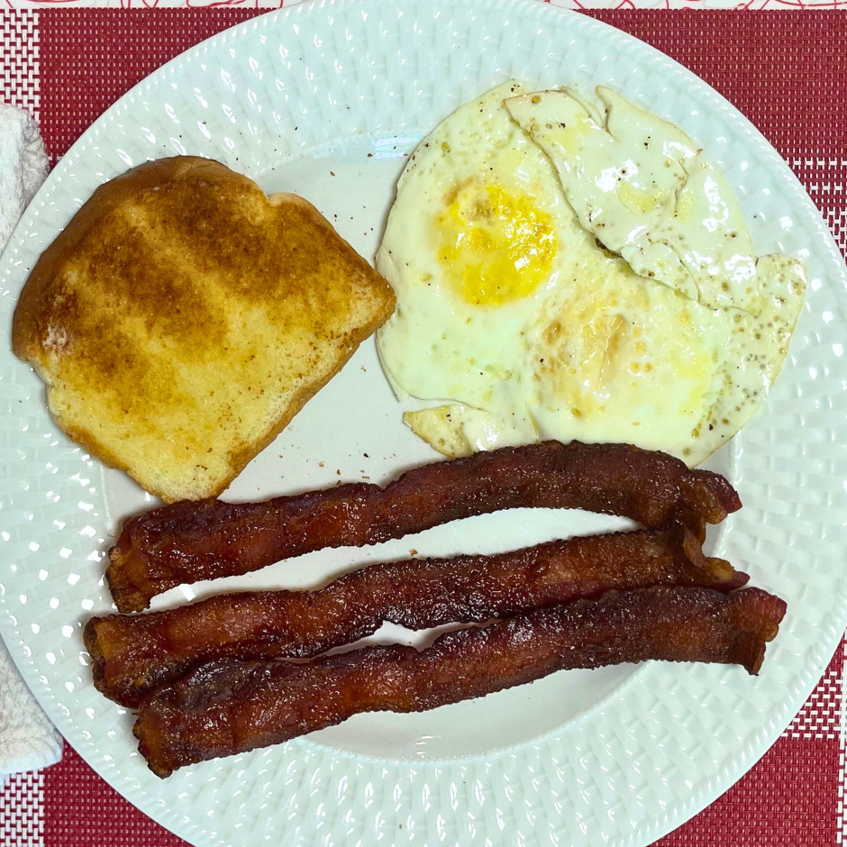 Bacon, eggs and toast on a white plate